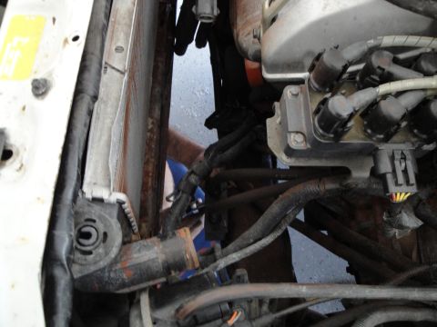 1989 Ford Taurus - A mechanic works on the engine bay, focusing on the radiator and ignition components.