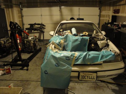 1989 Ford Taurus - A car is parked in a garage with its engine removed and the engine bay covered for protection.