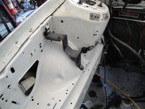 1989 Ford Taurus - Close-up of a custom engine bay bracket attached to the inner fender of a vehicle.