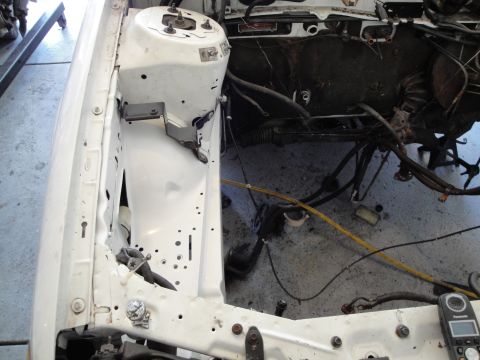1989 Ford Taurus - The engine bay of a white vehicle is shown with many components removed, indicating it is undergoing maintenance or an engine swap.