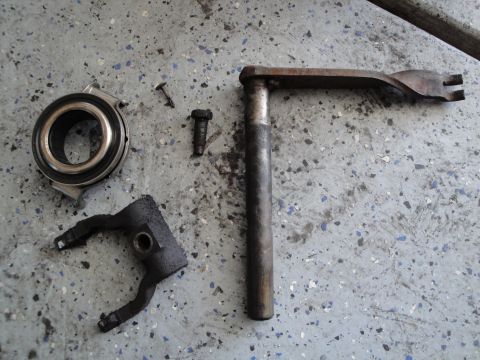 1989 Ford Taurus - Clutch fork, release bearing, and associated hardware laid out on a concrete surface.