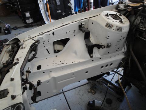 1989 Ford Taurus - The engine bay of a white car is shown with many components removed, revealing the internal structure.