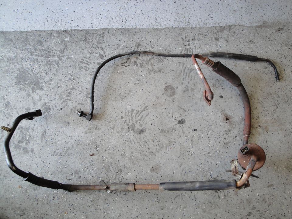 exhaust pipe assembly with a sensor attached, lying on a concrete surface