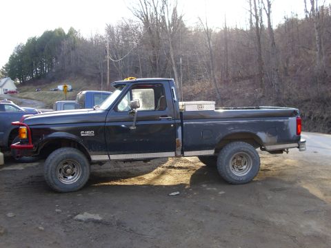 1995 Ford F-150 - This black Ford F-150 pickup truck is shown from the side, a custom red front bumper and a silver toolbox in the bed.