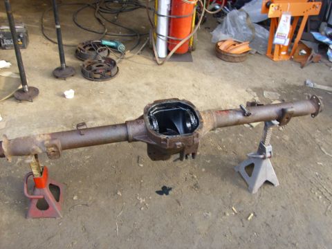 1995 Ford F-150 - A disassembled rear axle assembly sits on jack stands in a workshop setting, with tools and parts scattered around.