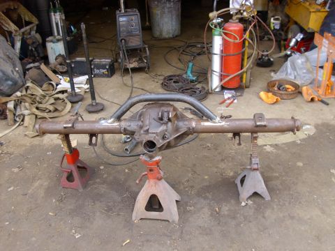 1995 Ford F-150 - Custom rear axle assembly, likely for a suspension modification, is supported by jack stands in a workshop setting.