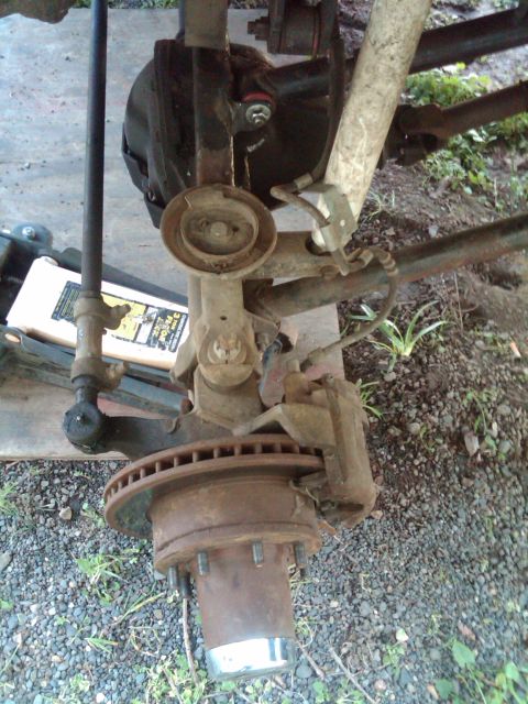 1978 Ford Bronco - This image shows a close-up of a vehicle's front axle, including the brake assembly and suspension parts.