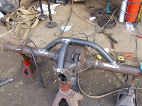 1995 Ford F-150 - Differential housing with custom tubing modifications, resting on jack stands amidst workshop clutter.