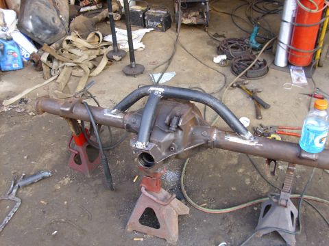 1995 Ford F-150 - A modified rear axle assembly is shown on jack stands in a workshop setting with various tools and parts nearby.