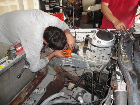 1989 Ford Taurus - Mechanic works on the engine bay of a car, with tools and parts scattered around.