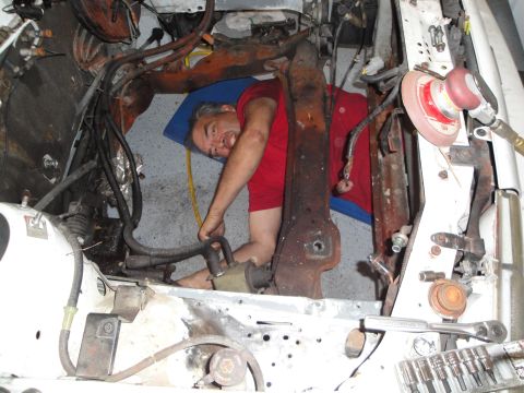 1989 Ford Taurus - Mechanic is working on the engine bay of a car, with various tools and parts around him.