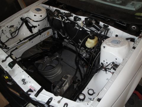 1989 Ford Taurus - The engine bay of a white car is shown with various components and wiring exposed.