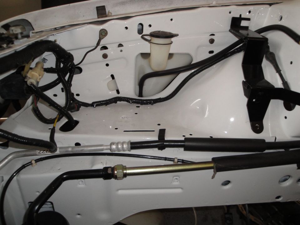 Engine bay with white paint, black hoses, and wiring harnesses