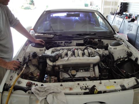 1989 Ford Taurus - Mechanic working on the engine of a 1989 Ford Taurus in a garage.