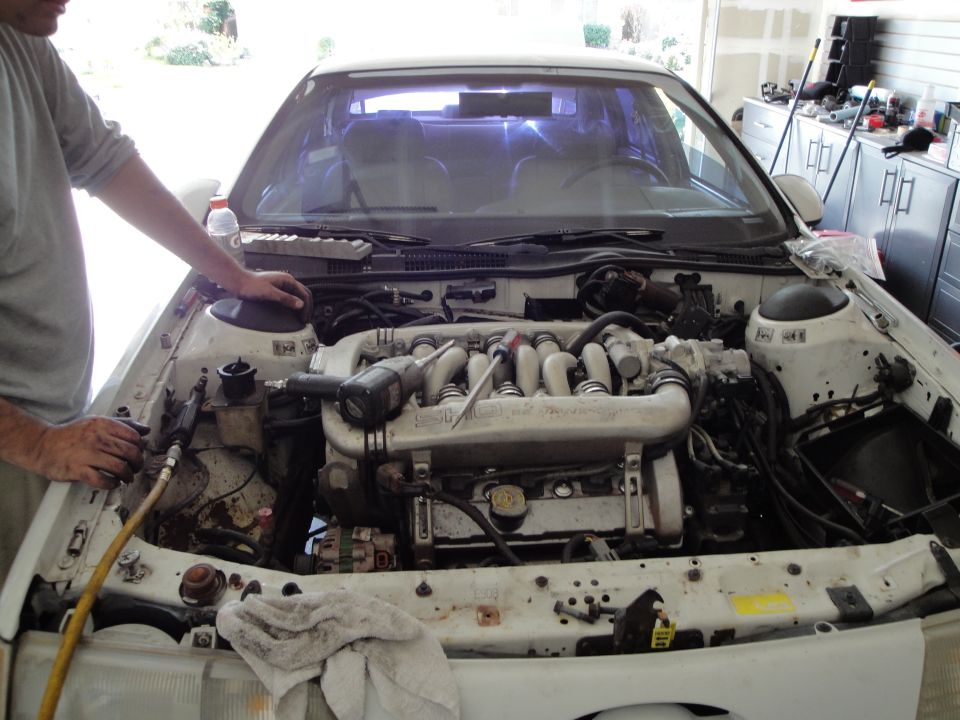 1989 Ford Taurus engine bay with a person working on the engine