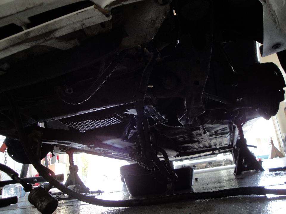 Underside of a car on jack stands with an oil pan underneath