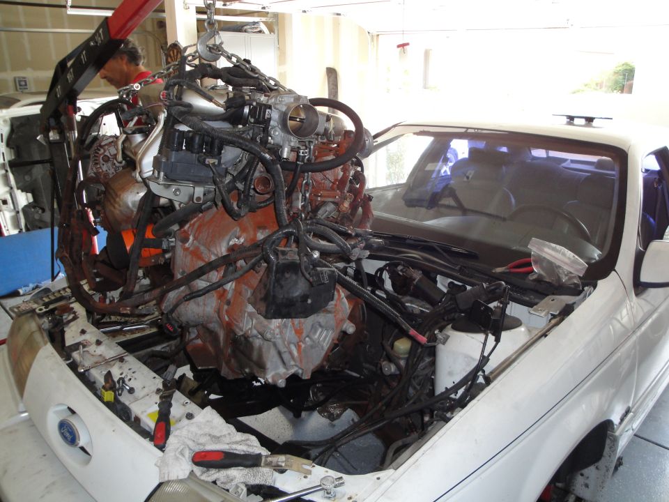 engine being lifted out of a white car with an engine hoist