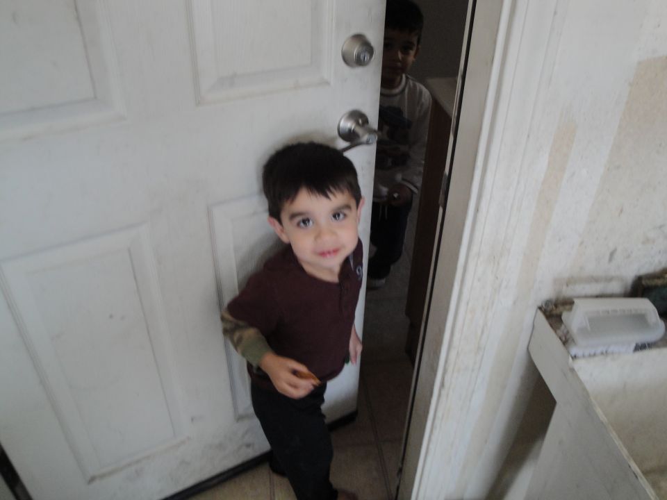 Two young boys stand in a doorway, one in the foreground looking at the camera, the other in the background