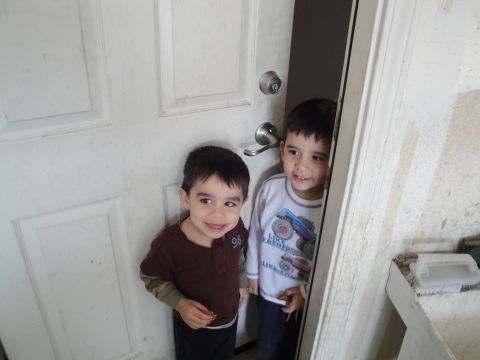 1989 Ford Taurus - Two boys are peeking out from behind a door.