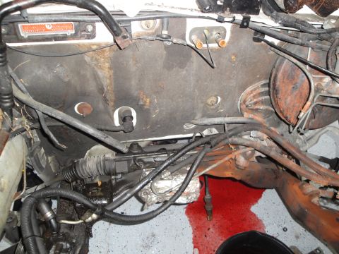 1989 Ford Taurus - The engine bay shows a significant red fluid leak and exposed mechanical components.