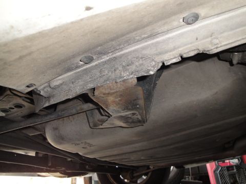 1989 Ford Taurus - The underside of a vehicle displays a fuel tank and corroded metal supports.