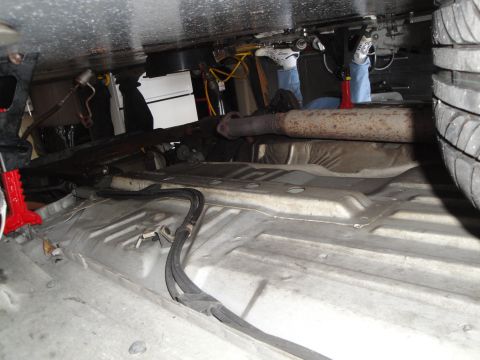 1989 Ford Taurus - The underside of a vehicle is visible, including the exhaust system, fuel lines, and a tire, suggesting maintenance or repair work.