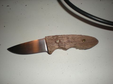 1974 Ford Ranchero - A handmade knife with a wooden handle is shown against a white surface, with a black cable overhead.