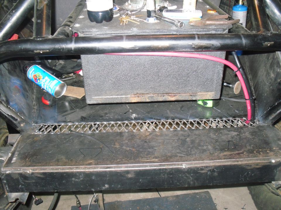 Inside of a custom vehicle with roll cage, speaker box, and wiring
