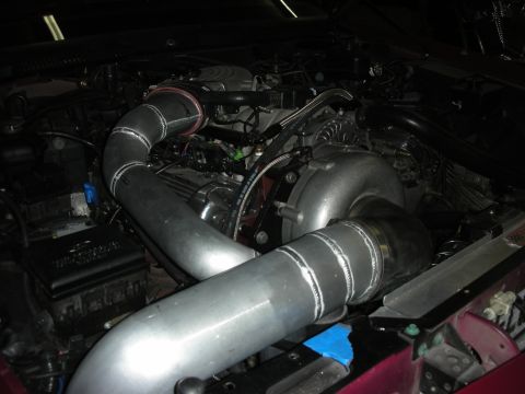 1992 Ford Crown Victoria - Custom turbocharger piping installed in an engine bay, obscuring most of the vehicle details.