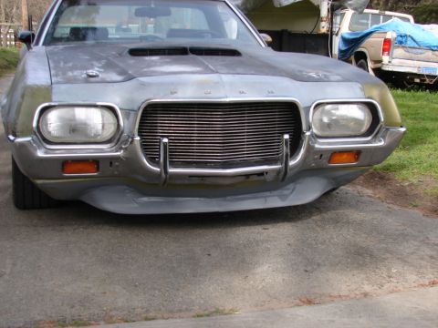 1973 Ford Ranchero - The front of a gray 1972 Ford Ranchero is visible, with a chrome grille and hood scoop, parked outdoors.