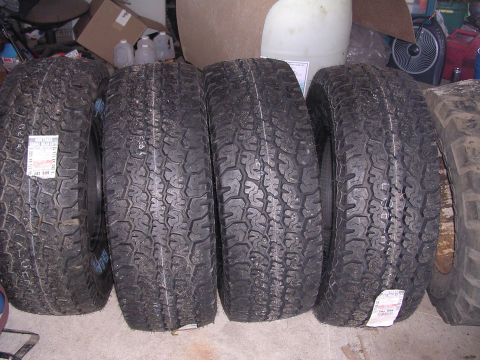 1979 Ford F-150 - A collection of four tires are displayed, with one tire showing a price tag with some text.