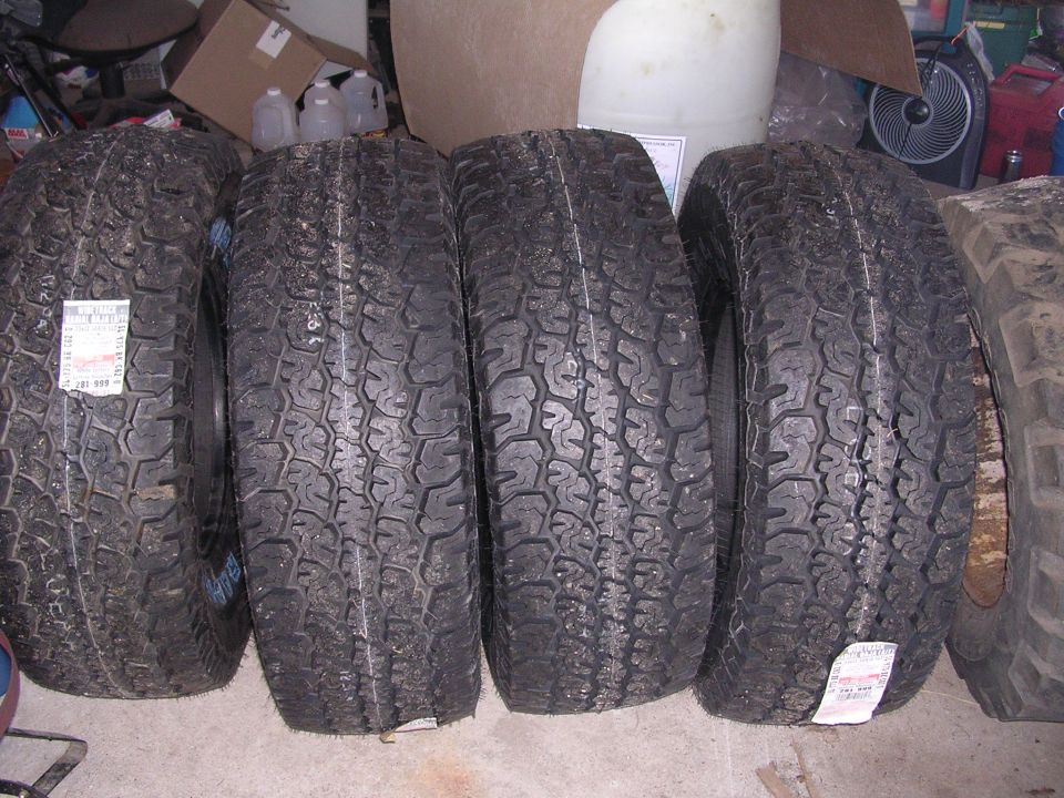 four tires lined up, one with a price tag