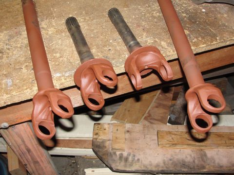 1995 Ford Bronco - Four driveshaft yokes, likely for a solid axle swap, are shown painted red and laid out on a wooden surface.