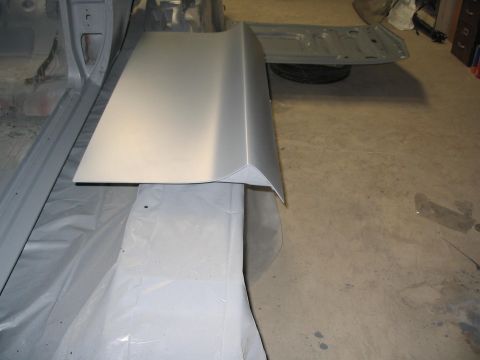1970 Ford Mustang - A car body panel is shown, primed and prepared for further work, with the trunk lid open in the background.