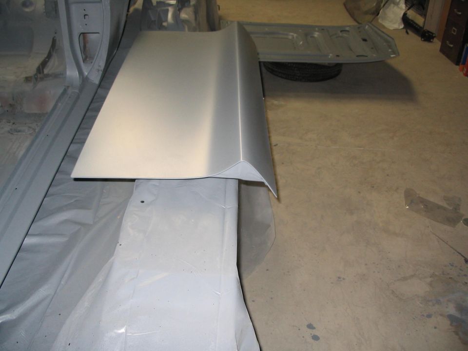 Car door or fender panel, primed and ready for paint. Trunk lid is open in the background