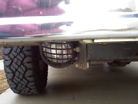 1992 Ford Bronco - Close-up of a front fog light with a protective grille, mounted beneath the vehicle's bumper.