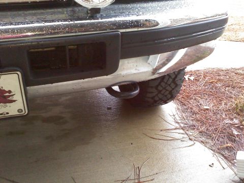 1992 Ford Bronco - Close-up of a vehicle's rear bumper and tire, with a tow hook attached.