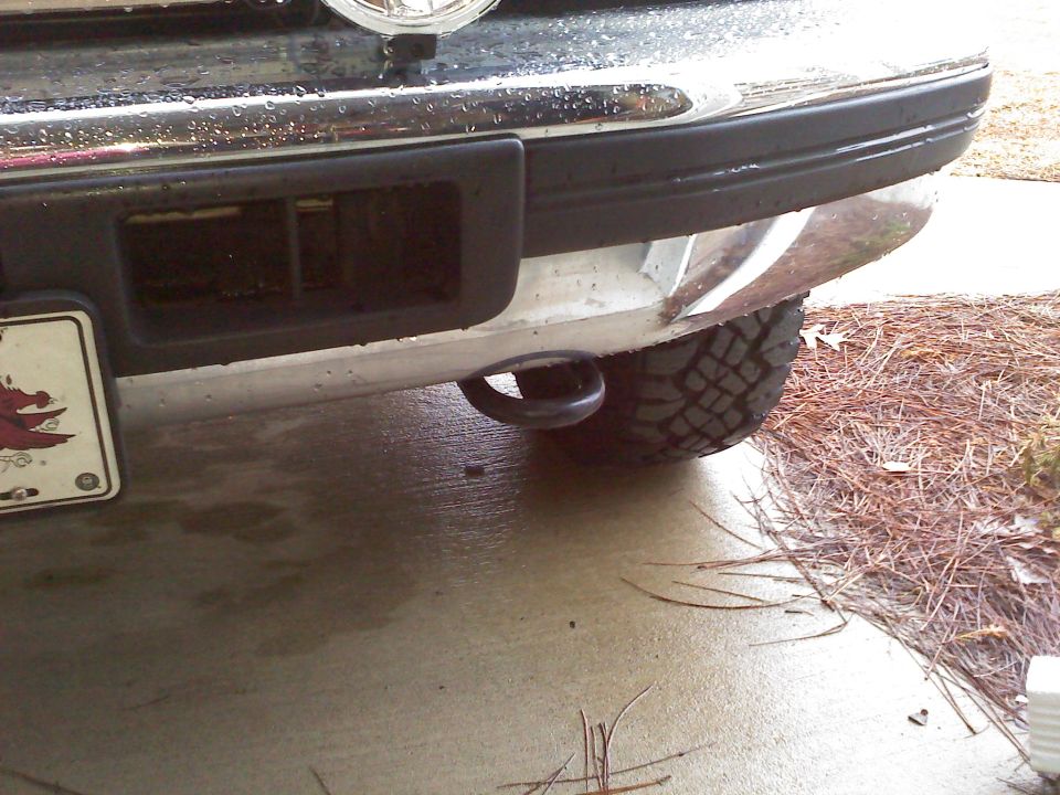 Rear bumper of a truck showing a tow hook and tire tread. License plate visible