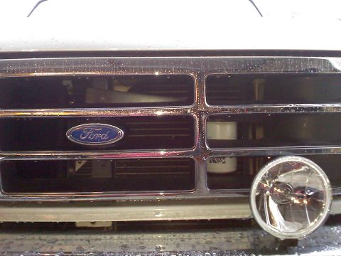 1992 Ford Bronco - Front view of a 1992 Ford Bronco grille, showing the Ford emblem and a headlight.