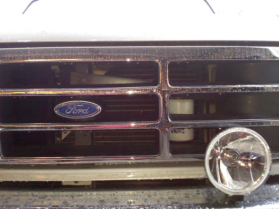 Chrome grille with Ford emblem, a round headlight, and water droplets