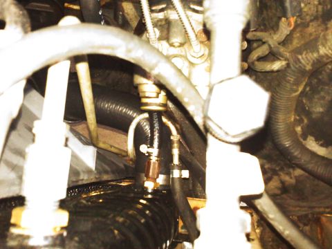 1992 Ford Bronco - Close-up view of engine components, including hoses and metal fittings. The image contains text identifying the website SUPERMOTORS.NET.