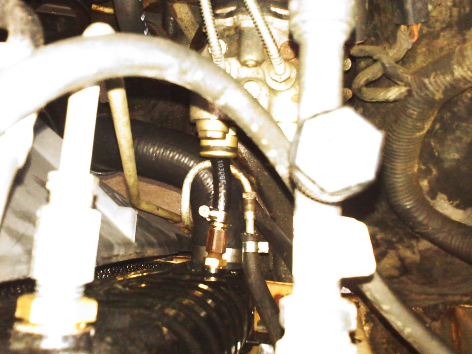 Engine compartment detail with hoses and fittings. Text reads SUPERMOTORS.NET