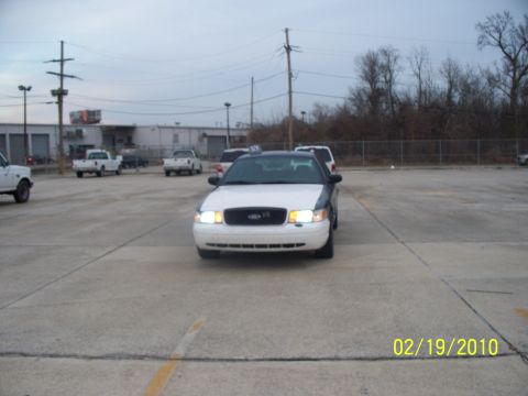 2005 Ford Crown Victoria - A 2005 Ford Crown Victoria police car is parked in a lot with other vehicles visible in the background.