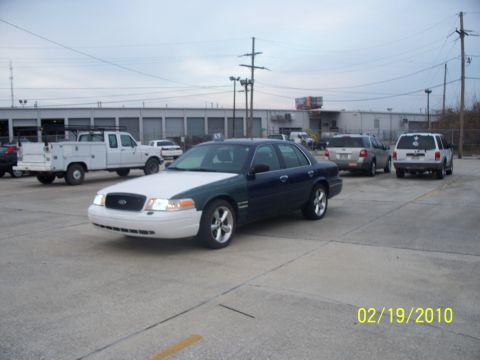 2005 Ford Crown Victoria - Two-tone 2005 Ford Crown Victoria parked outside a commercial building with other vehicles present.