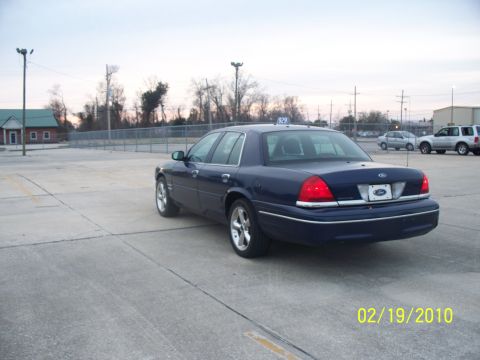 2005 Ford Crown Victoria - A dark blue sedan is parked in a lot with other vehicles visible in the background.