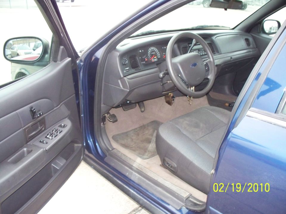 Blue 2005 Ford Crown Victoria interior, driver's side door open, showing dashboard, steering wheel, and front seat