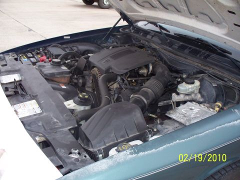 2005 Ford Crown Victoria - The engine compartment of a vehicle is shown with the hood open, revealing the engine components and a date stamp.