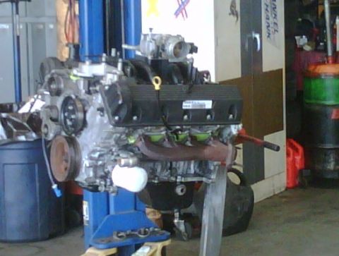 2005 Ford Crown Victoria - A V8 engine is mounted on a stand, ready for work in a cluttered garage environment.