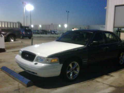 2005 Ford Crown Victoria - A two-tone Ford Crown Victoria is parked in a lot at dusk.