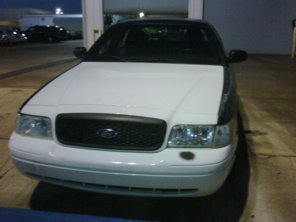 White 2005 Ford Crown Victoria front view, black grille with Ford logo, clear headlights, dark hood